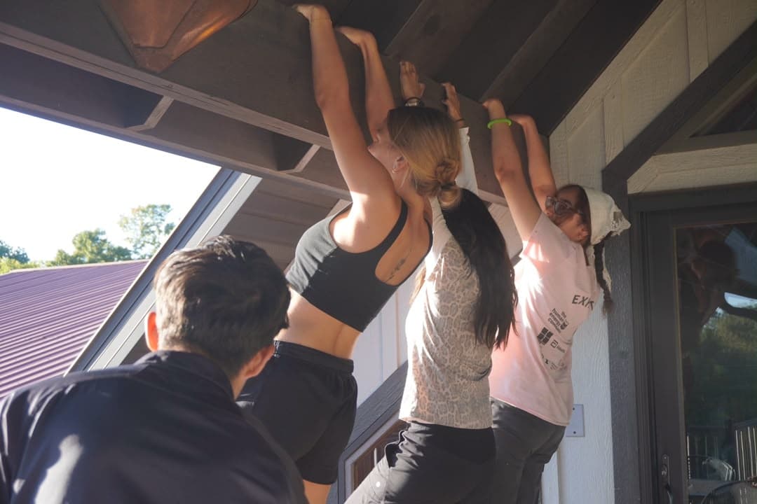 Friends reaching up to a porch rafter together